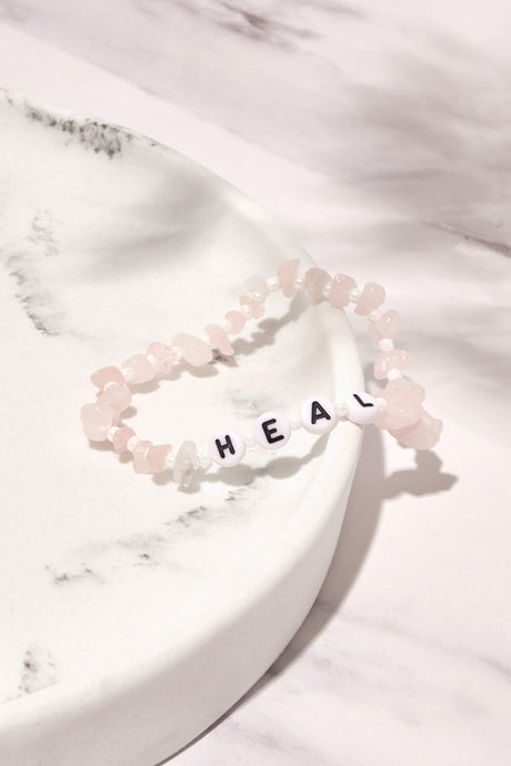 rose quartz heal crystal bracelet displayed on white marble background 