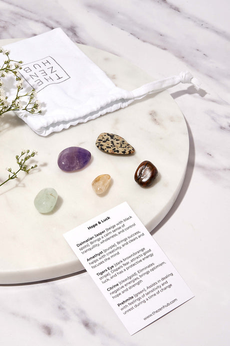 crystals designed to aid with hope and luck displayed on a white marble background. There is also a white drawstring bag and explanation card